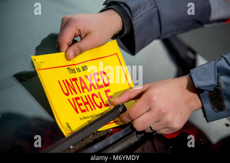 Wheel clamping of untaxed vehicles is becoming more common with the paper tax disc display being abolished and car tax needing to be paid online. Stock Photo