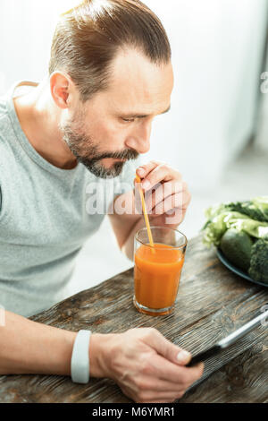 Calm handsome man using the tablet and drinking juice. Stock Photo