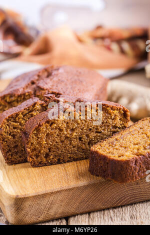 Healthy vegan freshly baked homemade pumpkin cake with ingredients on rustic wooden board, sliced and ready to eat Stock Photo