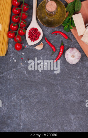 traditionally the Italian food background, with spaghetti, parmesan, olive oil, garlic, peppercorns, rosemary, cherry tomatoes, parsley and thyme. Stock Photo