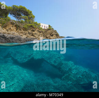 Spain Mediterranean coast with a small house and a natural rock formation underwater, split view over and under sea surface, Catalonia, Costa Brava Stock Photo