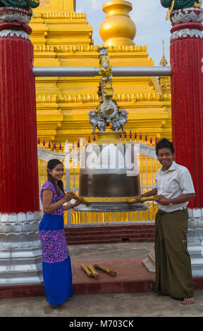 Visitors ring the bell at Kuthodaw Pagoda, Mandalay, Myanmar (Burma), Asia in February Stock Photo