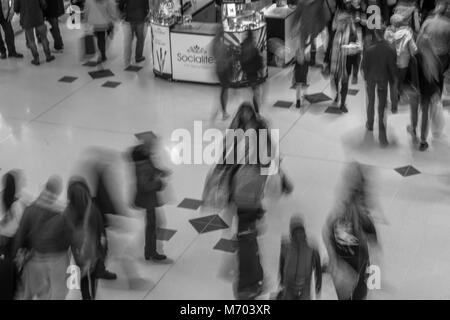 People walking through a shopping mall, taken with a slow exposure to blur the people and add the impression of rushing around Stock Photo