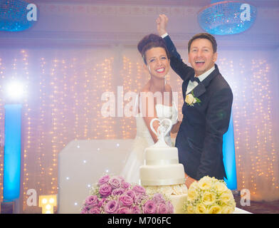 Smiling bride and groom cutting wedding cake on their wedding day Stock Photo