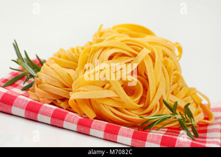 bundles of dried ribbon pasta on checkered place mat- close up Stock Photo