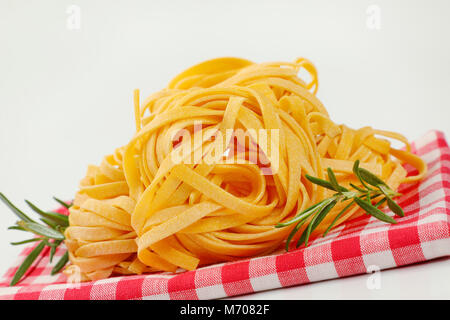 bundles of dried ribbon pasta on checkered place mat - close up Stock Photo