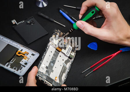 Process of repair of the broken phone. The disassembled smartphone and special tools. Stock Photo