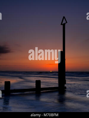 Groynes at sunset on the beach at Rhyl, North Wales coast Stock Photo