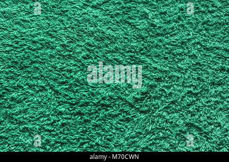 Abstract background of shaggy green carpet pile. Cloth texture with long fibers Stock Photo