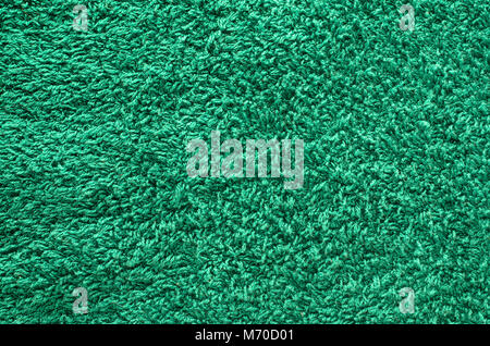 Abstract background of shaggy green carpet pile. Cloth texture with long fibers Stock Photo