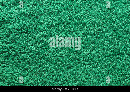 Abstract background of shaggy green carpet pile. Cloth texture with long fibers Stock Photo