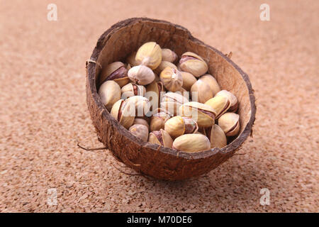 handmade bowl of coconut with pistachios on a wooden table. Close-up. Stock Photo