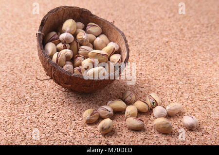 handmade bowl of coconut with pistachios on a wooden table. Close-up. Stock Photo