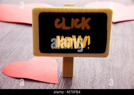 Handwriting text showing Click Now. Business photo showcasing Sign Book Or Register Banner For Join Apply written blackboard the wooden background wit Stock Photo