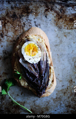Braised red chicory crostini with hummus, boiled egg and spices Stock Photo
