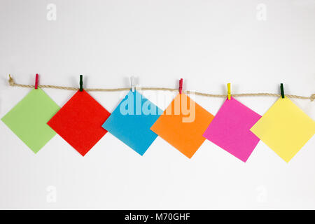 Sticky notes with small colored pegs in a rope in white background Stock Photo