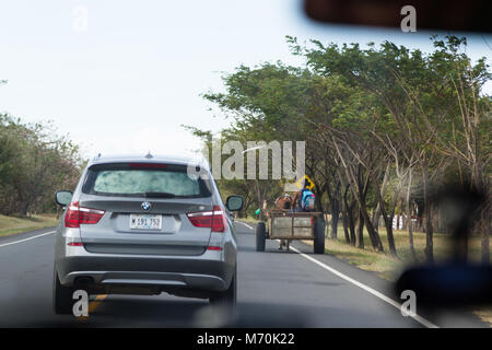 Peñas Blancas, Nicaragua - January 19: Man riding in a home made cart being pulled by a small horse on the Pan-American highway shot from inside a veh Stock Photo