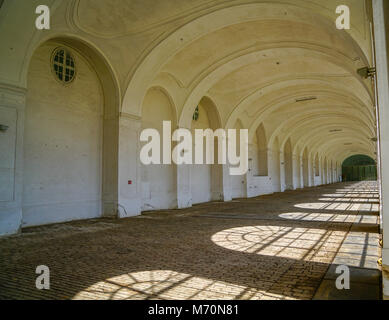 Classic vaulted archway leading along building with open side and sunlight casting repeating shadows through vaulted windows.. Stock Photo