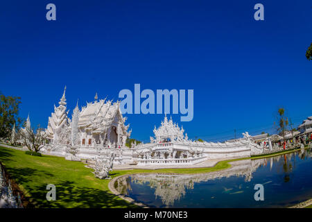 CHIANG RAI, THAILAND - FEBRUARY 01, 2018: Unidentified people taking pictures to white temple Wat Rong Khun located in Chiang Rai northern Thailand in sunny day with a natural pond Stock Photo