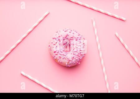 Pink donut and pink straws on pink background. Stock Photo