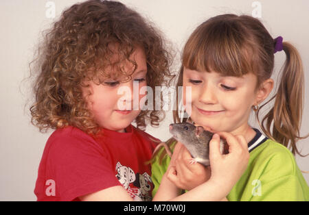 two little girls cuddling pet rat Stock Photo