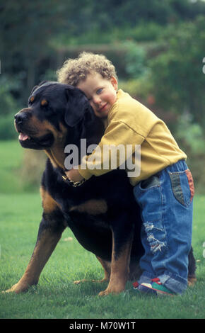 little boy cuddling Rottweiler dog Stock Photo