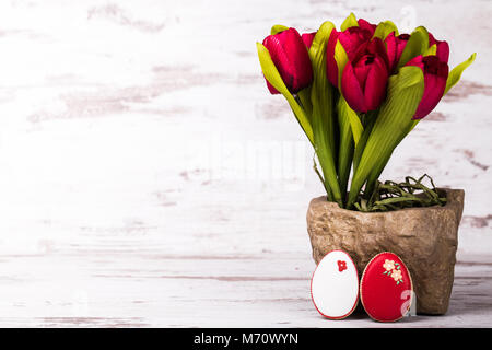 Easter gingerbread cookies and bouquet of tulips on wooden table.Beautiful glazed eggs. Greeting card. Copy space. Stock Photo