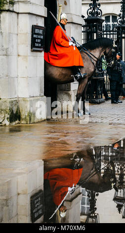 Mounted British guard on horse at Horse Guards parade ground on Whitehall, reflection on puddle - London tourist attraction Stock Photo