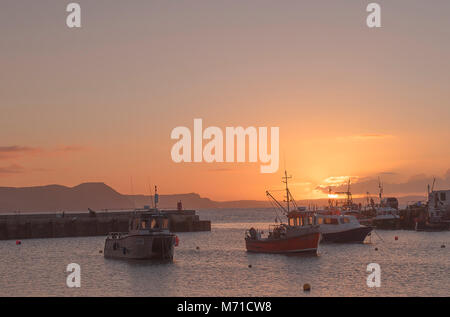 Lyme Regis, UK. 8th March, 2018. UK Weather: Glowing spring sunrise over the Historic Cobb harbour at the seaside resort of Lyme Regis. Credit: Celia McMahon/Alamy Live News Stock Photo