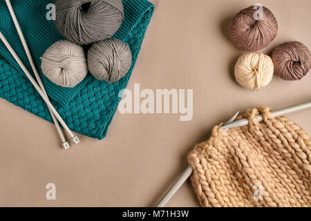 Grey and brown knitting wool and knitting on knitting needles on beige background. Top view. Copy space Stock Photo