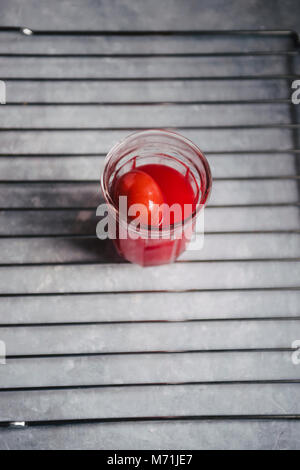 Red colored eggs with red tint are displayed on a metallic grate  top view over a gray concrete background Stock Photo