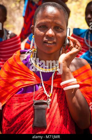 Tall Maasai Woman on her cell phone in colorful dress, lose-up, portrait, in Tanzania,Africa Stock Photo