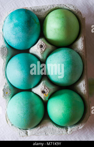 Packages with Dyed eggs for Easter holidays, colored  with red,blue,green and pink tint inside package are set over a gray concrete background Stock Photo