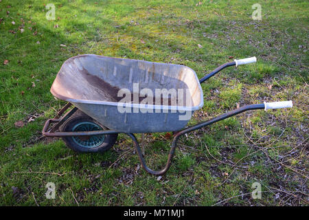 Used stainless steel wheelbarrow in the grass Stock Photo