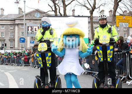 Gardai pose with Smurfs costume character on St. Patrick's Day in Dublin. Stock Photo