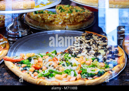 Pizza Take Away pieces on a stall, Traditional Italian Focaccia with tomatoes, black olives and cheese Pizza on a shop show-window Stock Photo