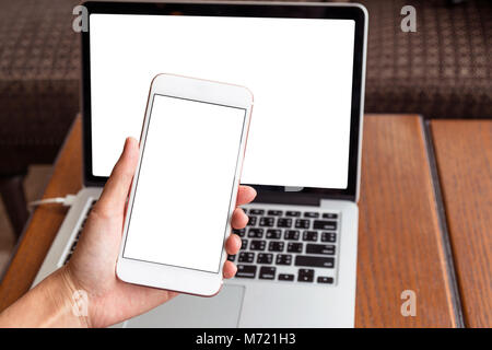 Hand holding the technology smart mobile phone shown white background for product mockup over the photo blurred of laptop with white background, busin Stock Photo