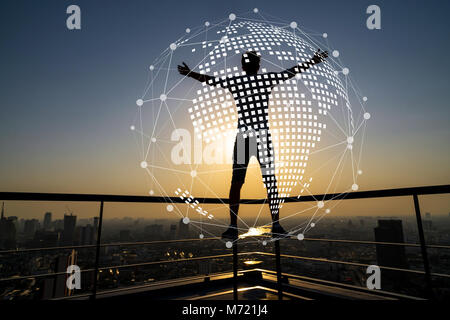 Silhouette of man standing with extend arms action over the cityscape background at sunset time with lens flare and Network graphic overlay background Stock Photo