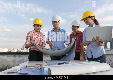 Multiethnic professional construction engineers working with Corporate Colleagues Teamwork and equipment blueprint,Safety glasses and laptop at the bu Stock Photo
