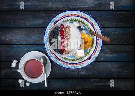 Sweet rice porridge with berries nuts and coconut chips with cutlery. Healthy breakfast or dessert. Bread with butter. Top view Stock Photo