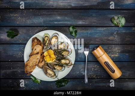 Mussels and bread toasts on on a white plate. Top view Stock Photo