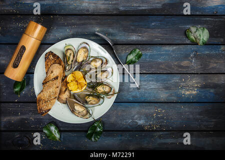 Mussels and bread toasts on on a white plate. Top view Stock Photo