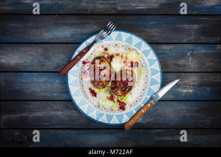 Turkey cutlets with a fresh berry saucea and iceberg salad served with cutlery. Stock Photo
