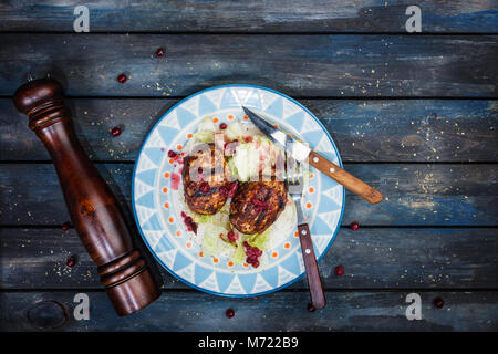 Turkey cutlets with a fresh berry saucea and iceberg salad served with cutlery and pepper grinder. Stock Photo