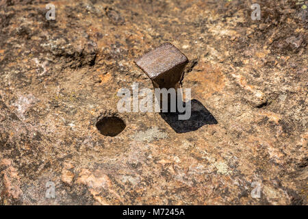 Iron nail in the rock with near the hole of an extracted nail Stock Photo