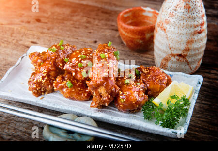 Korean style spicy crispy chicken mixed with red hot sticky sauce and onion top set ready to serve. Stock Photo