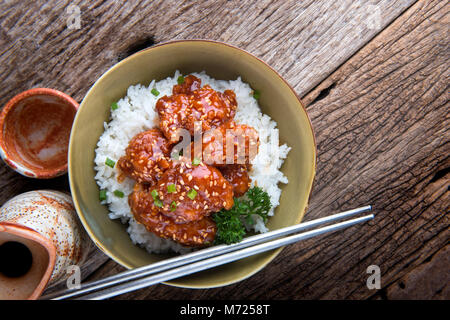 Korean style spicy crispy chicken mixed with red hot sticky sauce and onion top on rice set ready to serve. Stock Photo