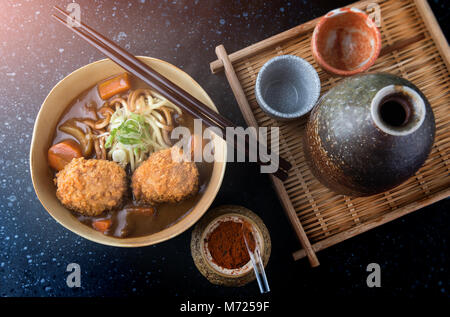 Japanese curry with udon noodle and crispy pork chop croquettes topping on bowl cup style. Stock Photo