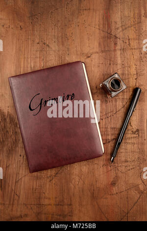 Leather bound journal titled Grimoire, and ink well and pen Stock Photo