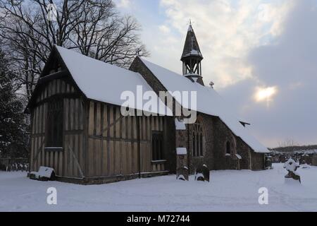 The Half - Timbered All Saints Church at Crowfield in Suffolk, England, under a layer of crisp white snow. Stock Photo